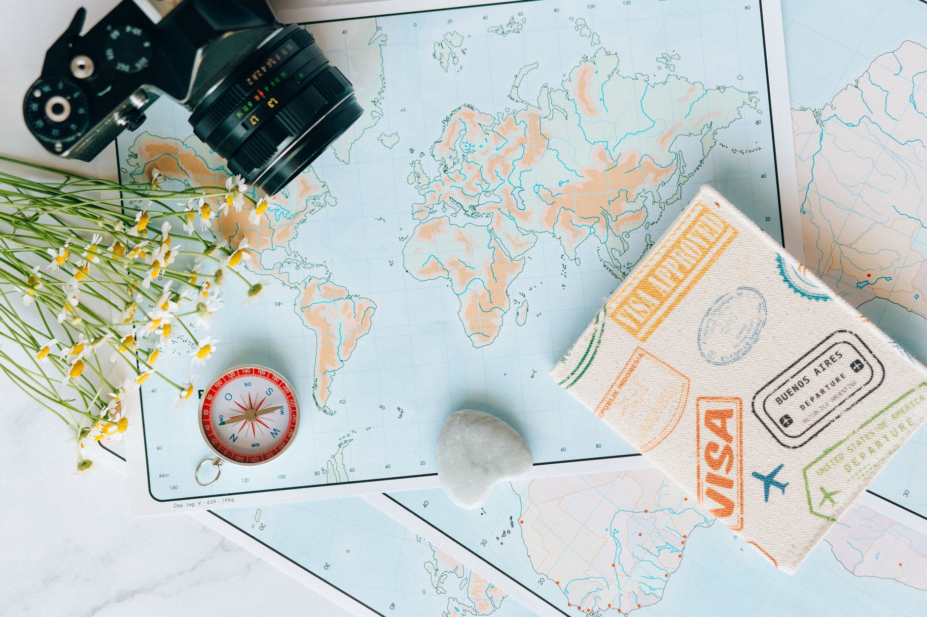 overhead shot of a camera and flowers near a map